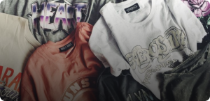 A pile of colorful printed t-shirts with various designs and logos.