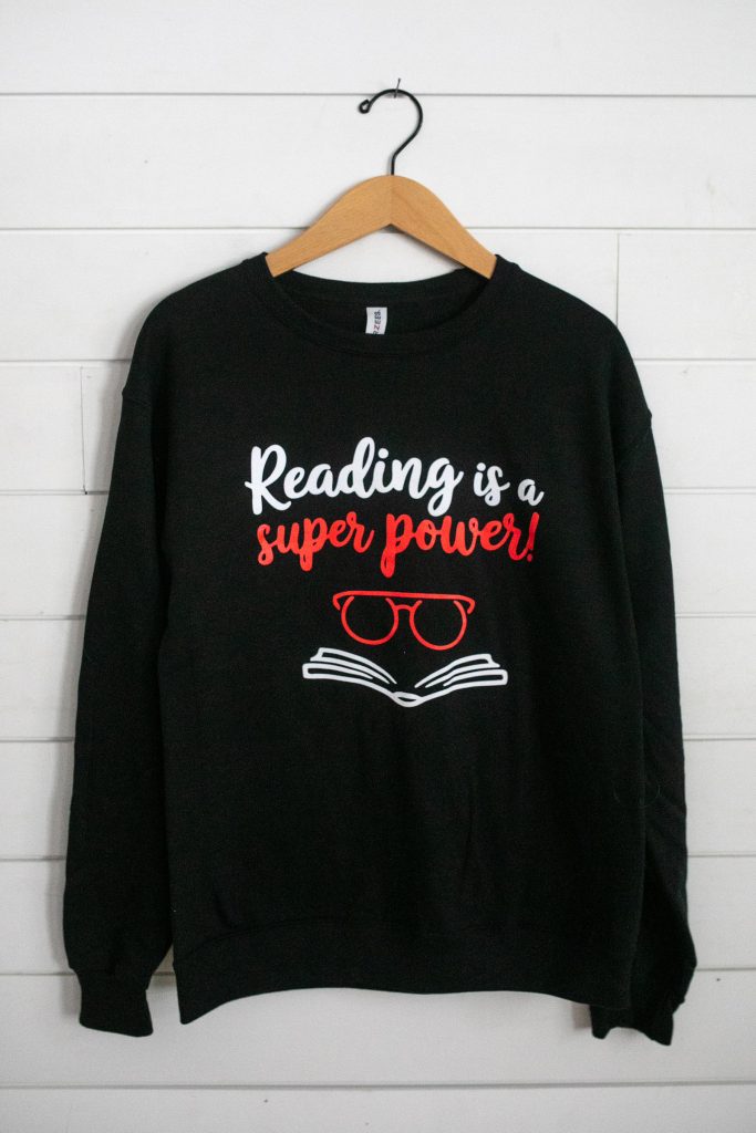 Black sweatshirt with 'Reading is a super power!' text and glasses graphic.